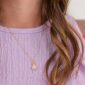 Gold ladybug necklace on purple blouse.
