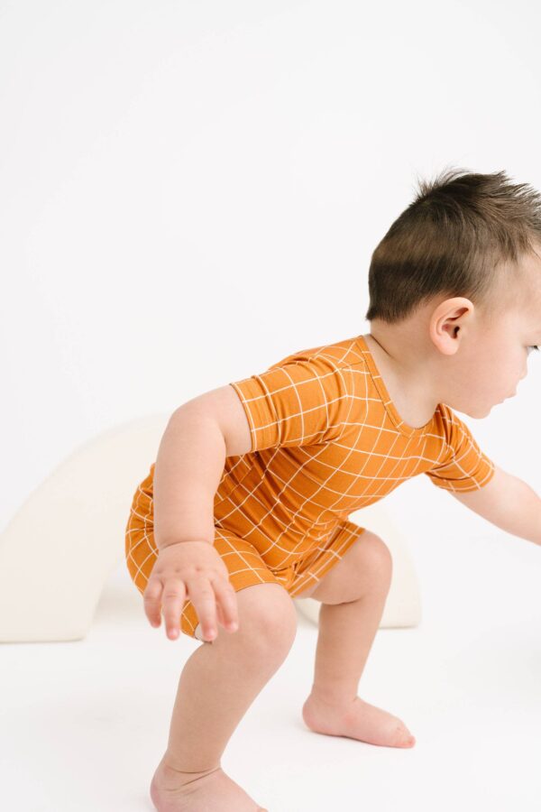 little one shop rust checks bamboo shorts set Toddler in orange grid-patterned outfit playing.