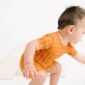 Toddler in orange grid-patterned outfit playing.