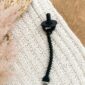 Black pacifier clip on knitted white fabric
