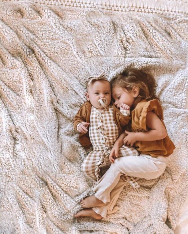 itzy ritzy sweetie soother™ pacifier sets (2 pack): agave + succulent cables Two children cuddling on a soft, beige blanket.