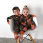 Two kids in camo pajamas sitting on a chair.
