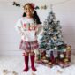 Child smiling near Christmas tree with gifts.
