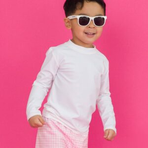 Child wearing sunglasses against pink background