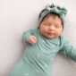 Sleeping baby in green outfit and headband.