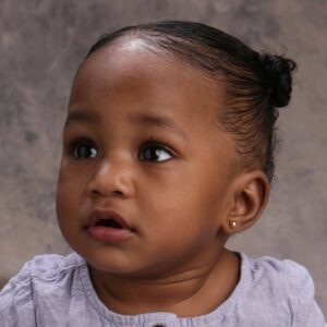 Baby with earrings looking upwards.