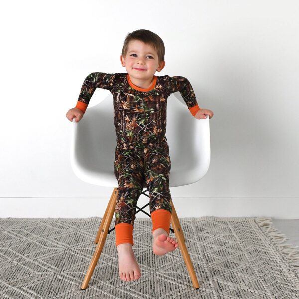 gigi and max hunter camo two piece no button bamboo outfit lounge Child sitting in chair wearing camouflage pajamas.