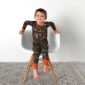 Child sitting in chair wearing camouflage pajamas.