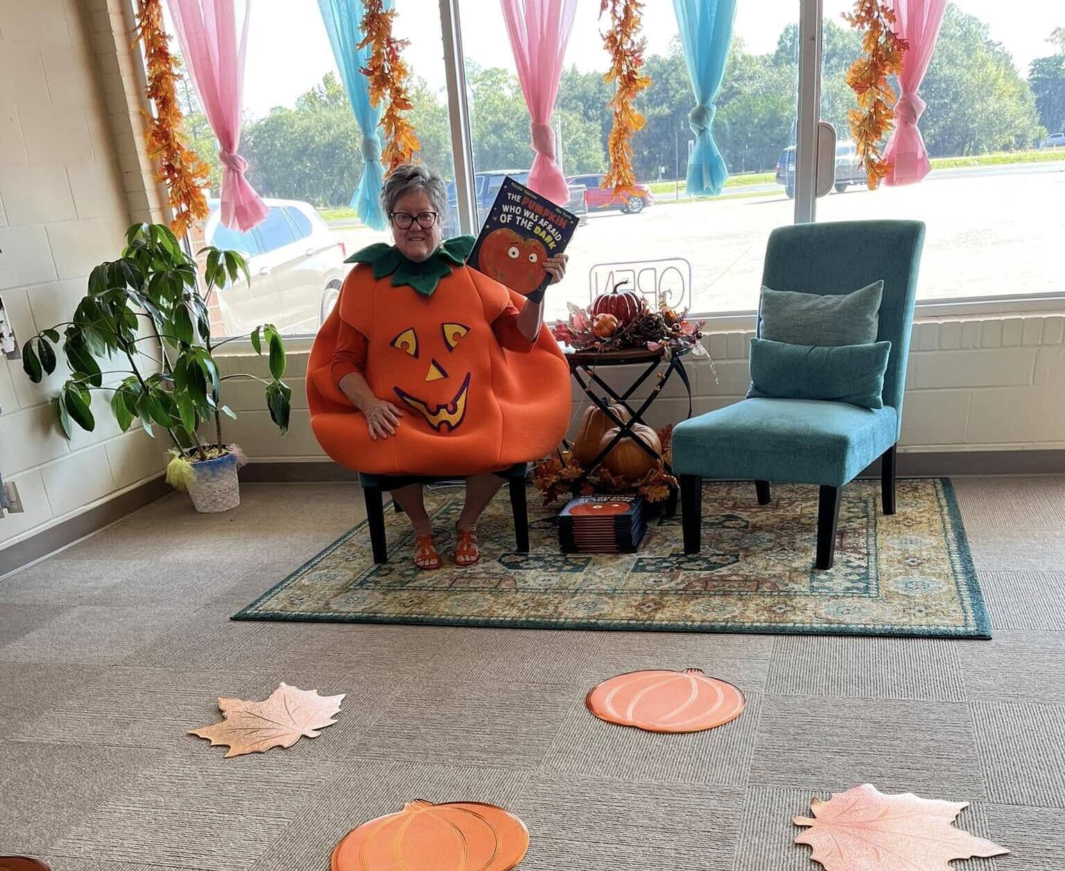 Person in pumpkin costume reading Halloween book